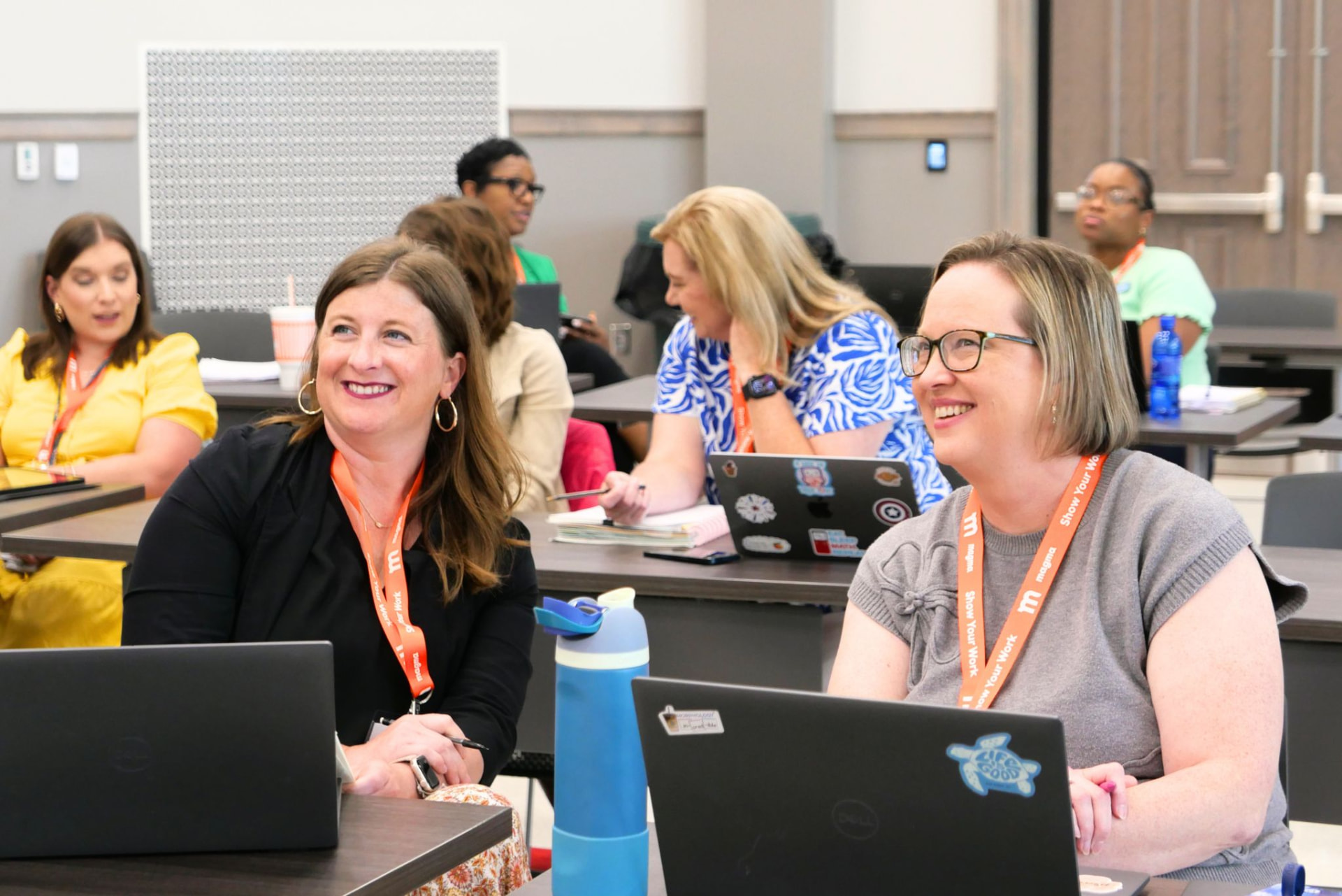 Smiling attendees with laptops engaged during a workshop session at a corporate event